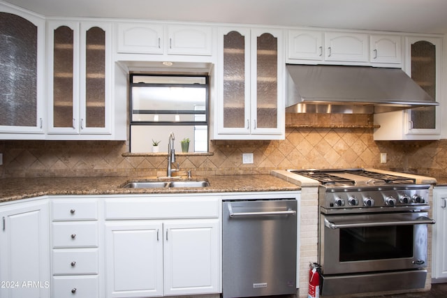 kitchen with sink, tasteful backsplash, wall chimney exhaust hood, white cabinetry, and stainless steel appliances