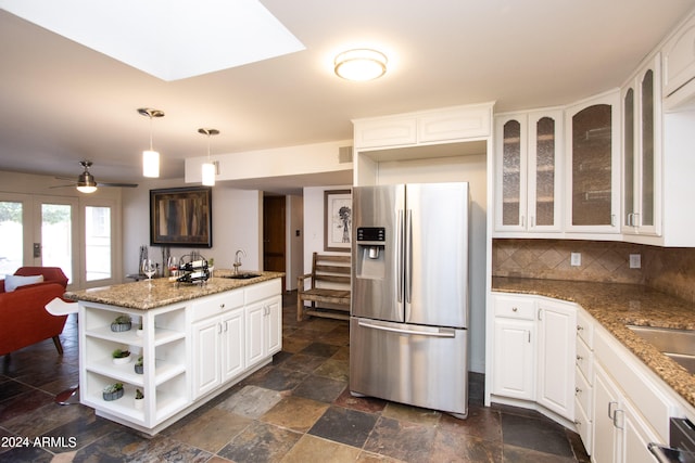 kitchen with white cabinets, hanging light fixtures, stainless steel fridge with ice dispenser, and decorative backsplash