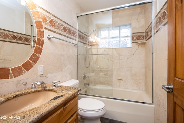 full bathroom with vanity, bath / shower combo with glass door, tile walls, toilet, and decorative backsplash