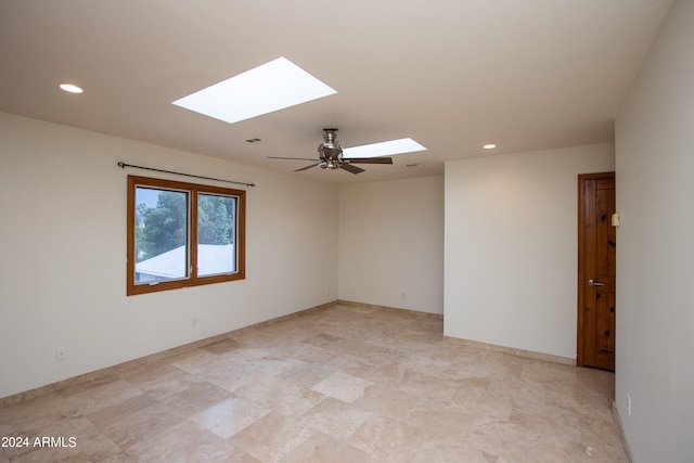 empty room with ceiling fan and a skylight