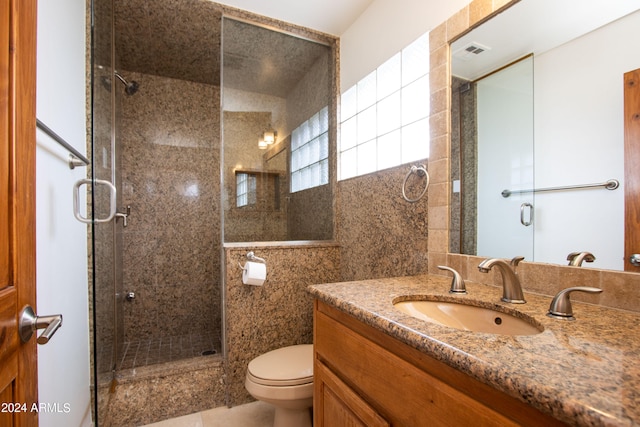 bathroom featuring tile walls, a shower with door, vanity, and toilet