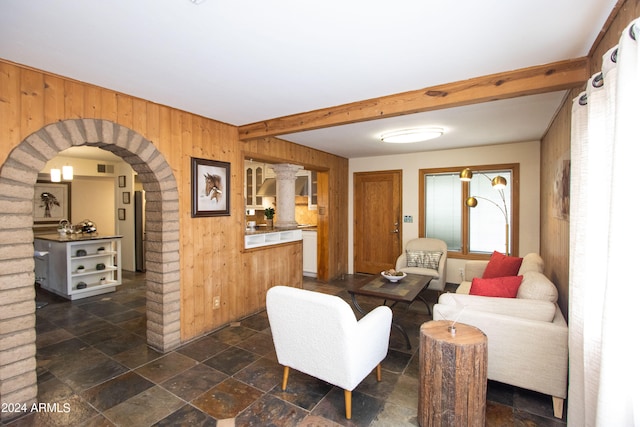 living room with wooden walls and beam ceiling