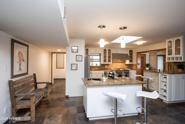 kitchen featuring a kitchen breakfast bar, decorative backsplash, a kitchen island, sink, and stainless steel range