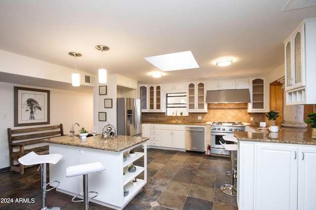 kitchen featuring appliances with stainless steel finishes, hanging light fixtures, white cabinetry, and a skylight