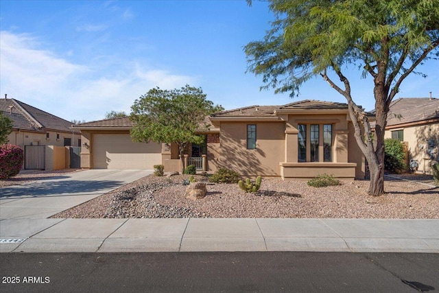 view of front of home featuring a garage, fence, driveway, a tiled roof, and stucco siding