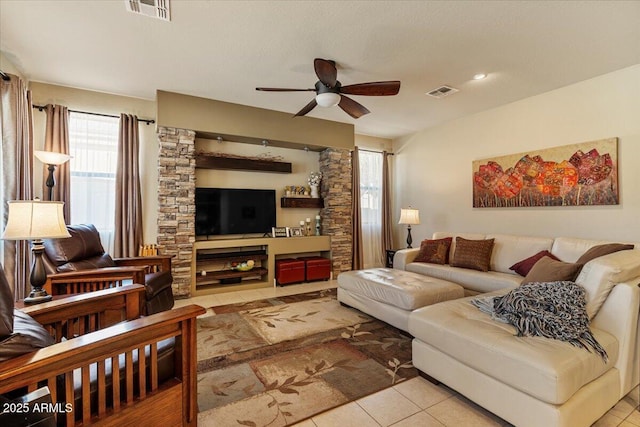living room with a ceiling fan, visible vents, and light tile patterned floors