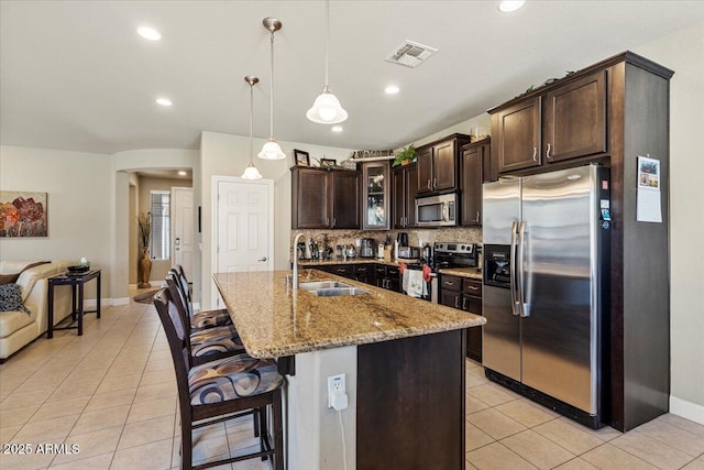 kitchen with dark brown cabinetry, visible vents, glass insert cabinets, stainless steel appliances, and a sink