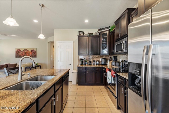 kitchen with hanging light fixtures, appliances with stainless steel finishes, glass insert cabinets, dark brown cabinetry, and a sink