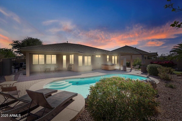 back of property with a fenced in pool, a patio area, and stucco siding