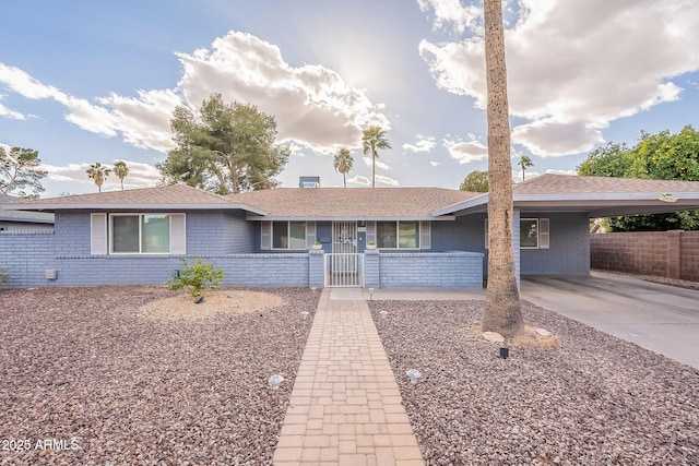 single story home with concrete driveway, an attached carport, fence, a porch, and brick siding