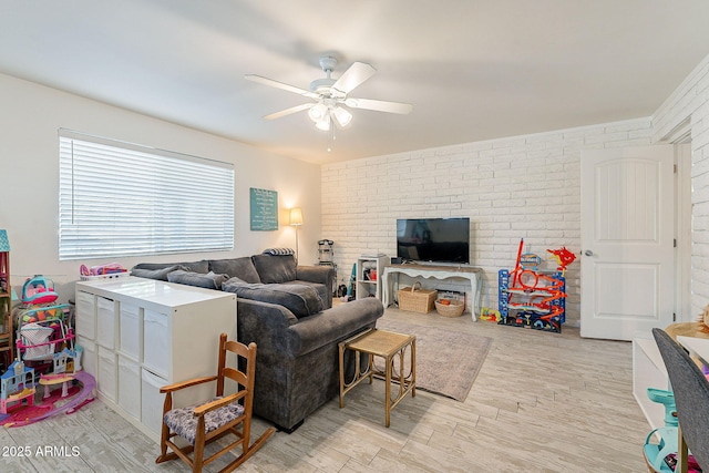 living area featuring brick wall, ceiling fan, and wood finished floors