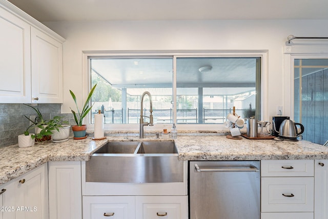 kitchen with a sink, white cabinetry, stainless steel dishwasher, decorative backsplash, and light stone countertops