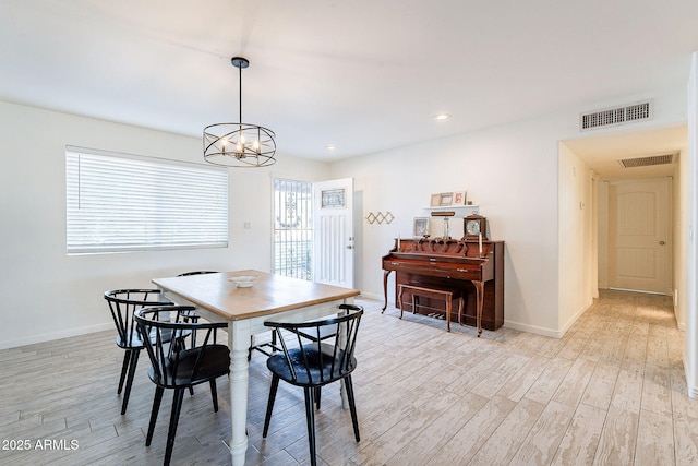 dining area featuring a healthy amount of sunlight, light wood-style flooring, visible vents, and a chandelier