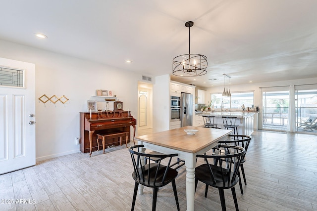 dining room with recessed lighting, baseboards, visible vents, and light wood finished floors