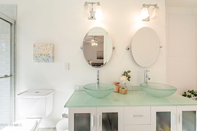 bathroom featuring double vanity, toilet, a sink, and a shower with shower door