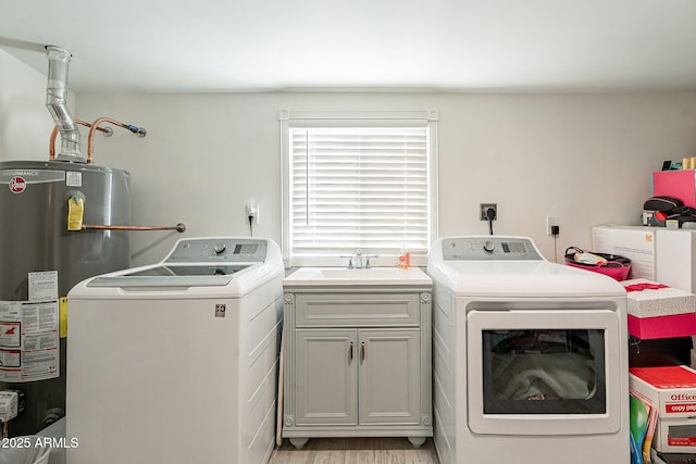 clothes washing area with gas water heater, separate washer and dryer, a sink, light wood-style floors, and cabinet space