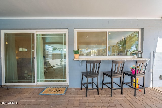 view of exterior entry with outdoor dry bar, a patio, and a sink