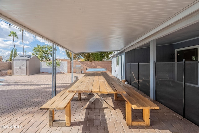 view of patio with a storage shed, outdoor dining area, an outbuilding, and a fenced backyard