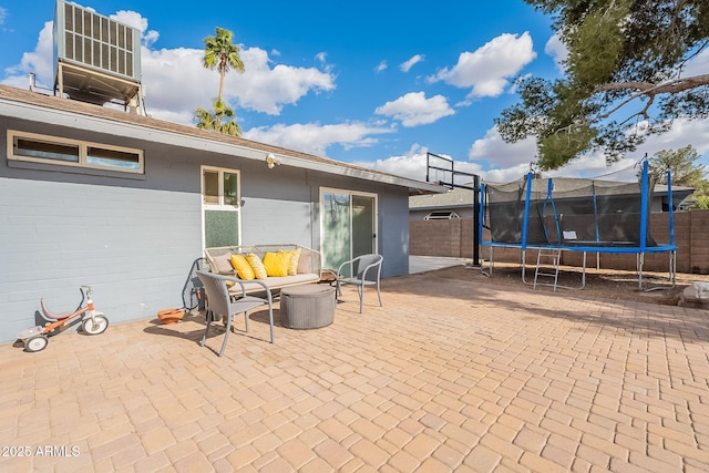 view of patio with a trampoline, cooling unit, and fence