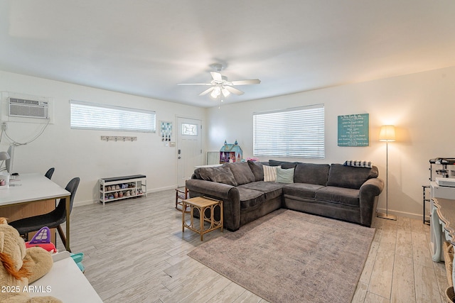 living area with light wood-style floors, baseboards, a ceiling fan, and a wall mounted AC