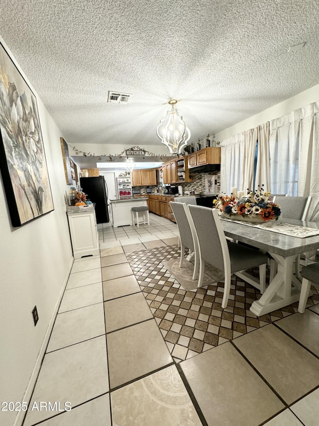 dining room with a textured ceiling, light tile patterned flooring, and a chandelier