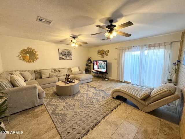 living room with ceiling fan and a textured ceiling