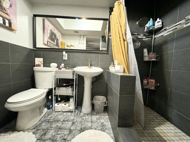 bathroom featuring tile walls, toilet, and a tile shower