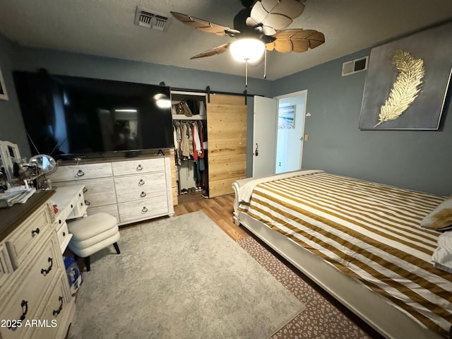 bedroom with ceiling fan, a closet, and a barn door