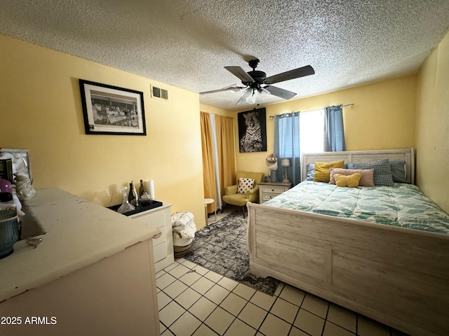 tiled bedroom with ceiling fan and a textured ceiling