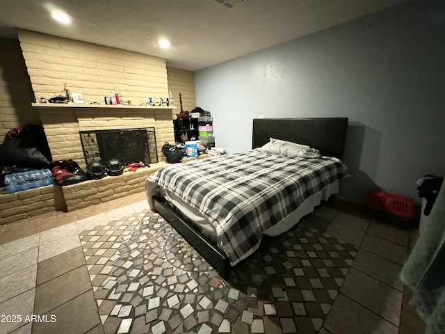 tiled bedroom featuring a stone fireplace