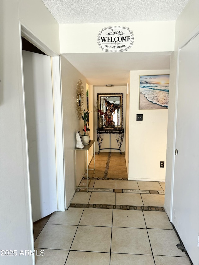 hallway featuring a textured ceiling and light tile patterned flooring