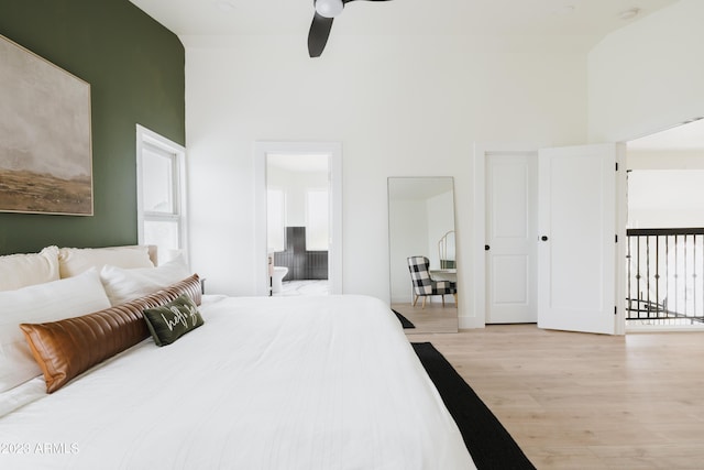 bedroom with ceiling fan, a towering ceiling, ensuite bathroom, and light wood-type flooring