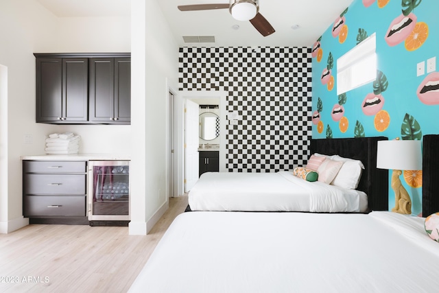 bedroom featuring light hardwood / wood-style floors, beverage cooler, ceiling fan, and ensuite bathroom