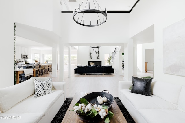 living room featuring wood-type flooring, a high ceiling, and a notable chandelier