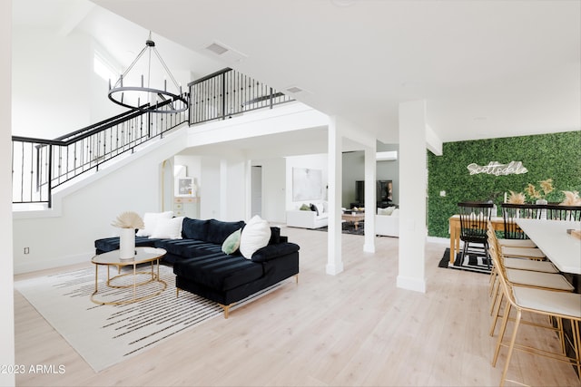 living room featuring a towering ceiling, a notable chandelier, and light wood-type flooring