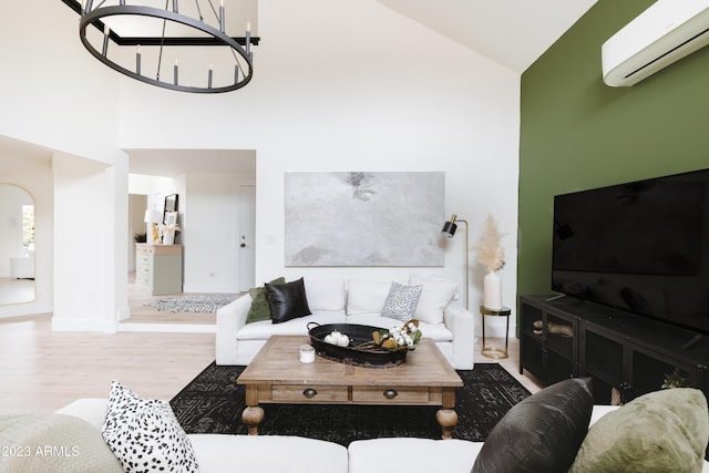 living room with high vaulted ceiling, hardwood / wood-style floors, a notable chandelier, and a wall unit AC