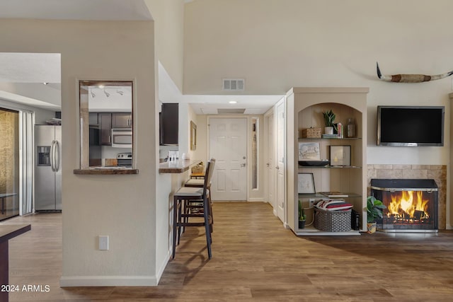 kitchen featuring stainless steel appliances, visible vents, wood finished floors, and a tile fireplace