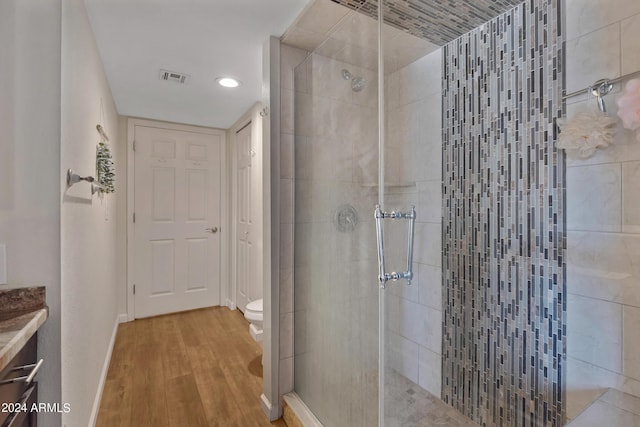 full bath featuring a shower stall, toilet, wood finished floors, and visible vents