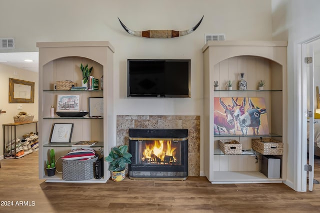 living room featuring built in features, visible vents, wood finished floors, and a tile fireplace