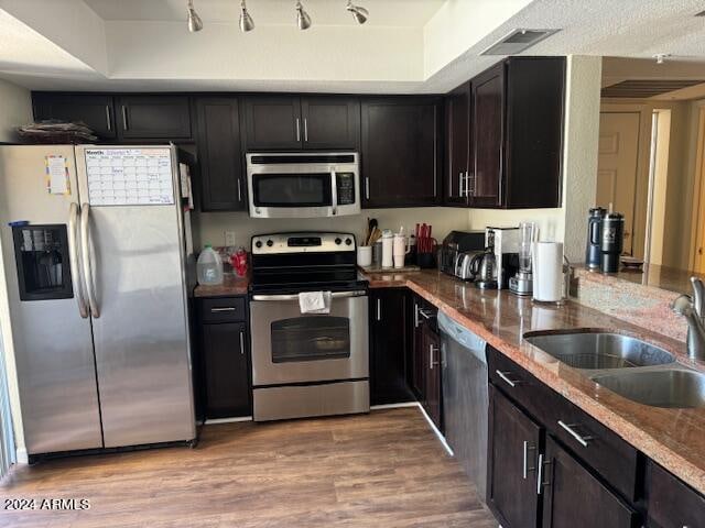 kitchen with sink, appliances with stainless steel finishes, stone counters, and light hardwood / wood-style floors