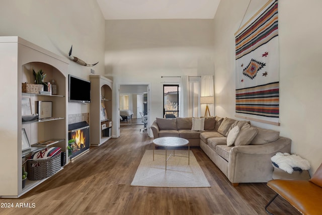 living room featuring a high ceiling, wood finished floors, and a fireplace