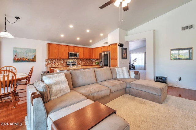 living room with wood-type flooring, sink, ceiling fan, and high vaulted ceiling