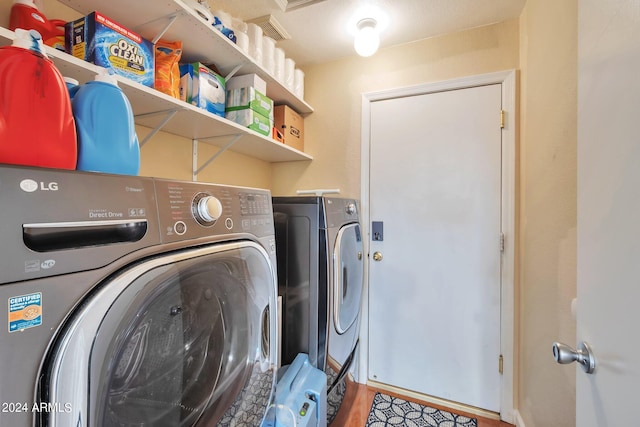 laundry room with wood-type flooring and washing machine and dryer