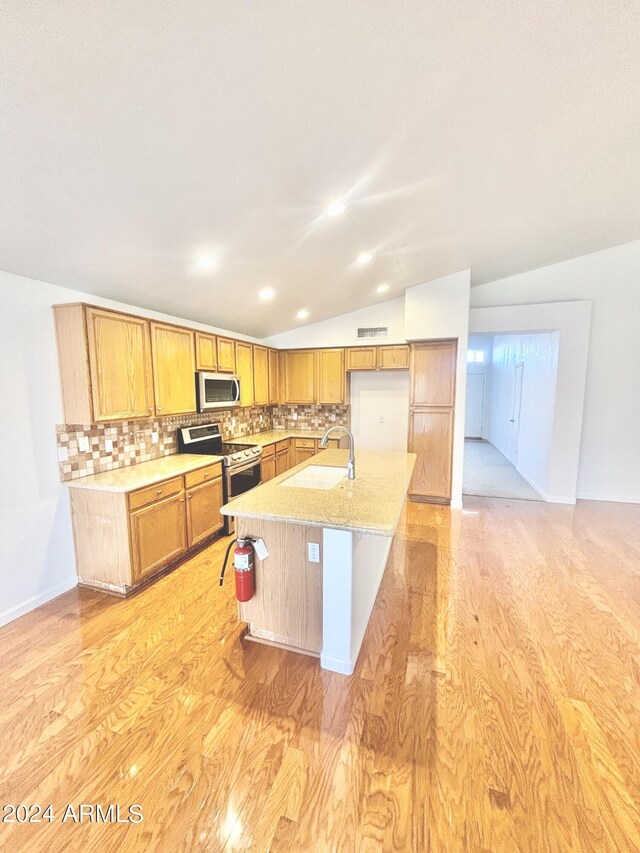 kitchen featuring light stone countertops, stainless steel appliances, backsplash, and light hardwood / wood-style floors