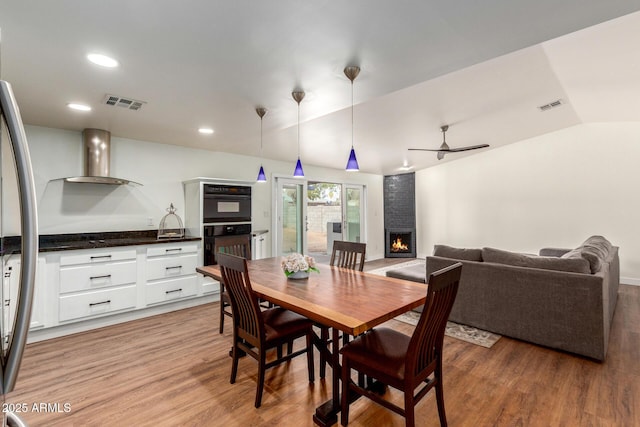 dining space featuring light wood finished floors, visible vents, and vaulted ceiling