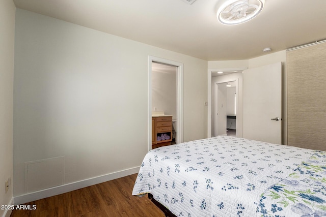 bedroom featuring baseboards, dark wood finished floors, and ensuite bathroom