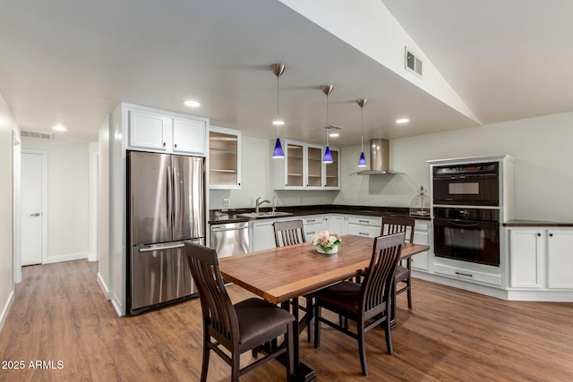 kitchen featuring dark countertops, wall chimney exhaust hood, visible vents, and appliances with stainless steel finishes