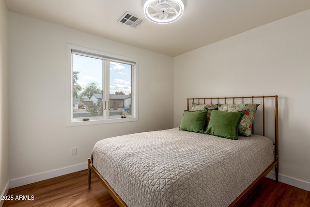 bedroom with baseboards, visible vents, and wood finished floors