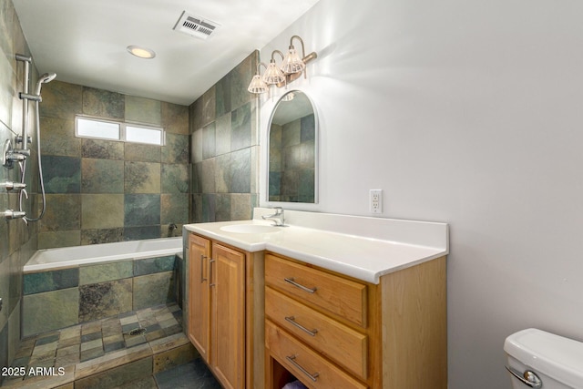 full bath with tiled shower / bath, visible vents, vanity, and toilet