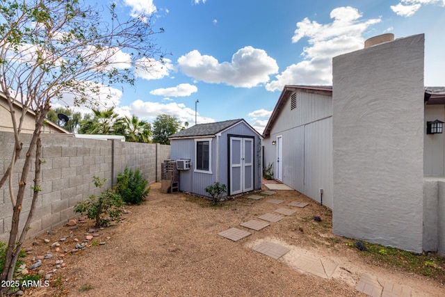 view of yard featuring a shed, a fenced backyard, and an outdoor structure